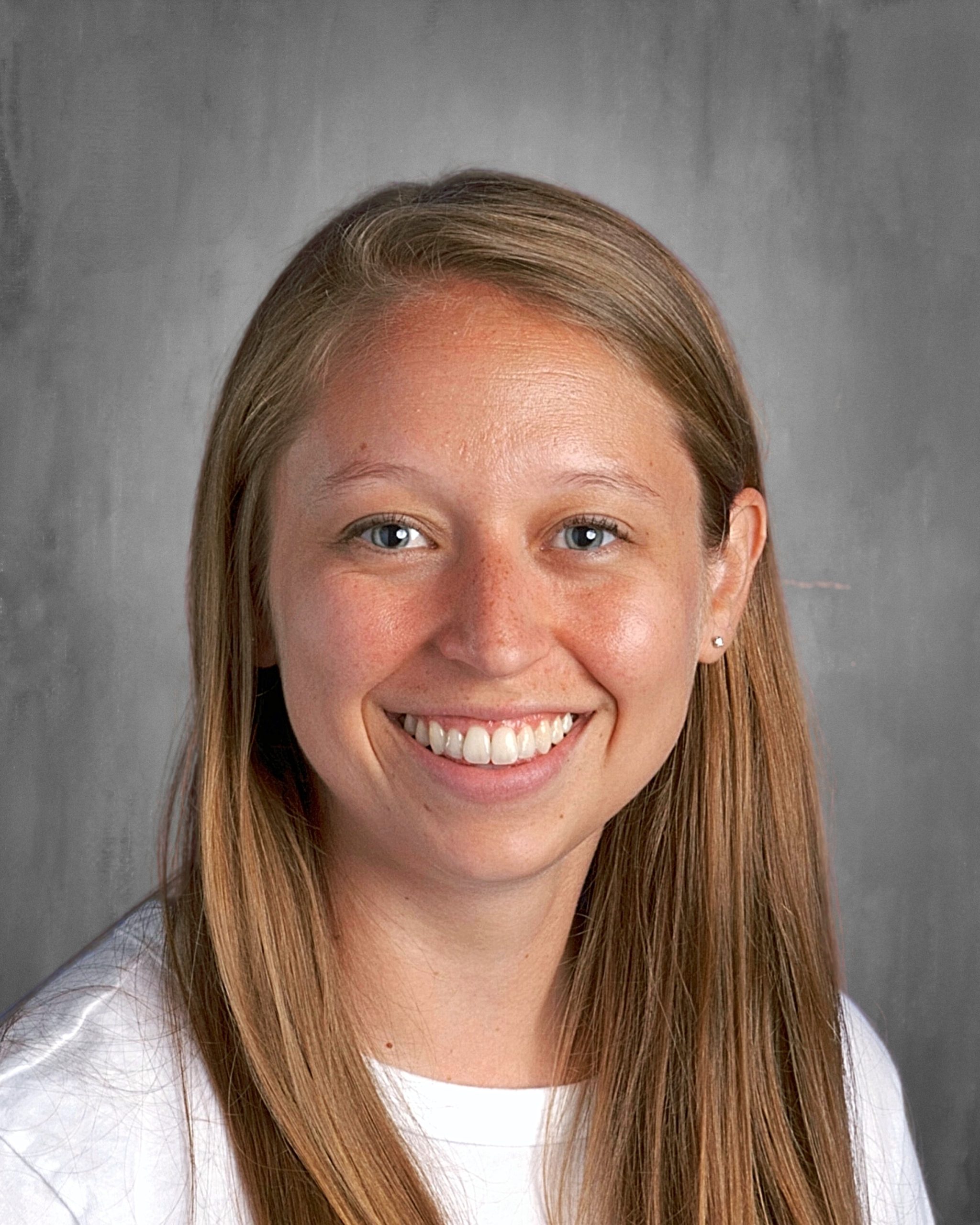 Smiling person with long hair against a gray background.